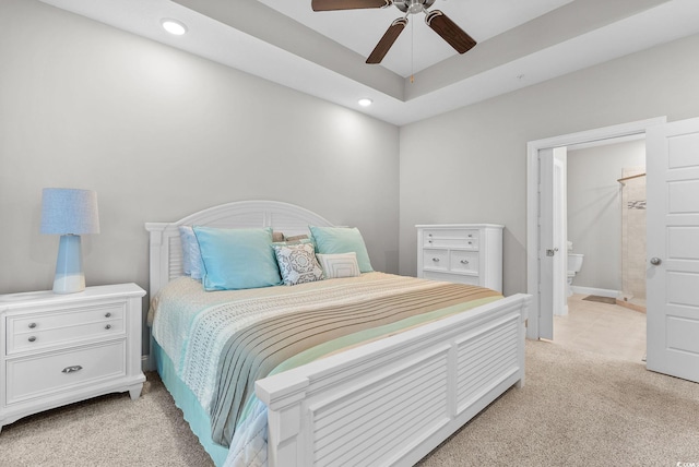 bedroom featuring ceiling fan, ensuite bath, and light colored carpet