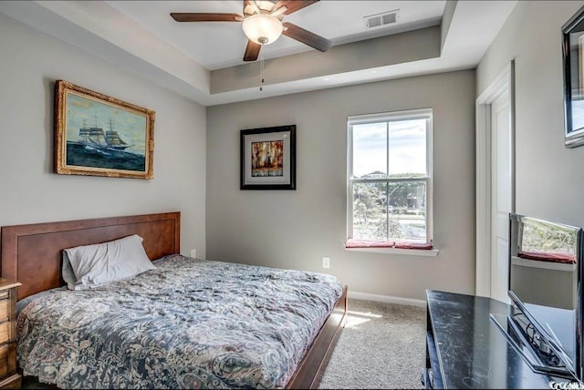 bedroom with ceiling fan, a raised ceiling, and carpet floors