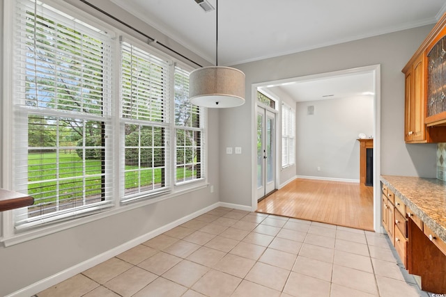 unfurnished dining area featuring light tile patterned floors, a wealth of natural light, and ornamental molding