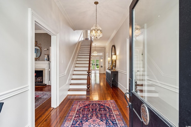 entryway featuring a notable chandelier, dark wood-type flooring, and ornamental molding