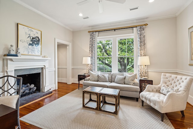 living room with ceiling fan, a premium fireplace, crown molding, and hardwood / wood-style flooring