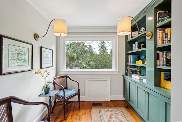 living area with light wood-type flooring and ornamental molding