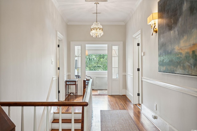 foyer featuring crown molding, wood-type flooring, and a chandelier