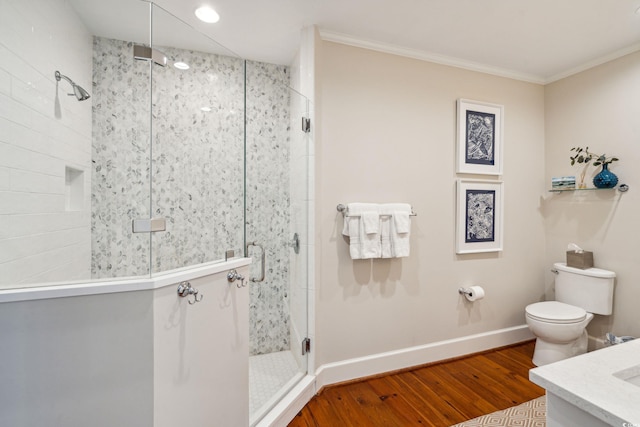 bathroom with crown molding, hardwood / wood-style flooring, a shower with door, toilet, and vanity