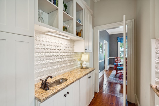 kitchen with white cabinetry, dark wood-type flooring, crown molding, backsplash, and sink