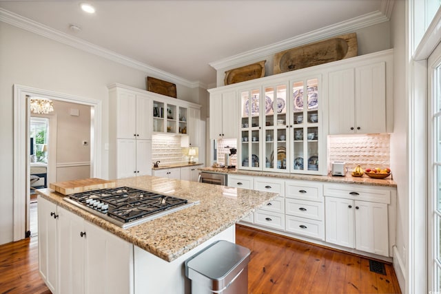 kitchen with decorative backsplash, stainless steel gas stovetop, dark hardwood / wood-style flooring, and white cabinetry