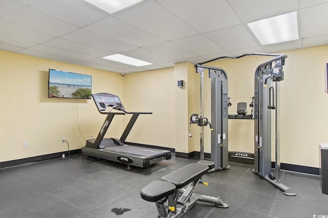 workout room with a paneled ceiling and concrete flooring