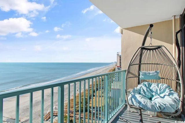 balcony with a water view and a view of the beach