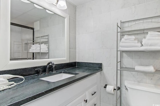 bathroom with tile walls, toilet, and vanity