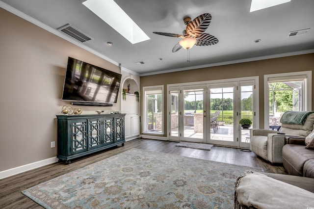 living room with hardwood / wood-style floors, a skylight, ornamental molding, and ceiling fan