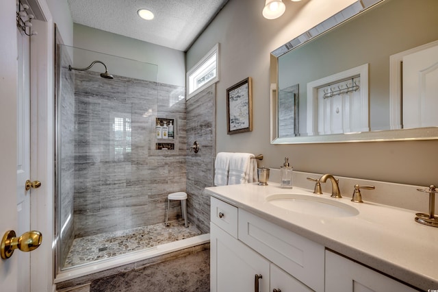 bathroom featuring vanity, a textured ceiling, and tiled shower