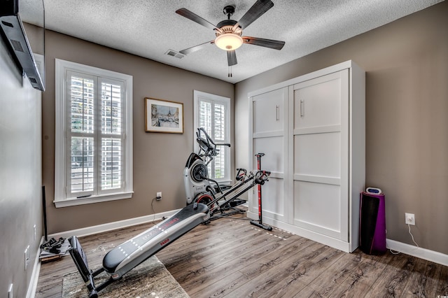 workout area with ceiling fan, a wealth of natural light, a textured ceiling, and hardwood / wood-style floors