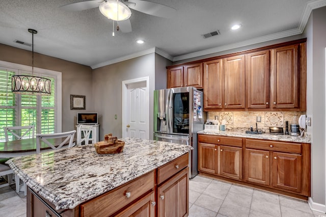 kitchen with decorative backsplash, ceiling fan with notable chandelier, stainless steel fridge, light tile patterned flooring, and a kitchen island