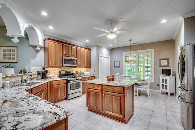 kitchen featuring sink, a center island, hanging light fixtures, appliances with stainless steel finishes, and decorative backsplash