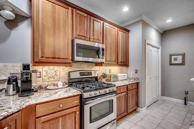 kitchen with a textured ceiling, light stone counters, appliances with stainless steel finishes, light tile patterned floors, and backsplash