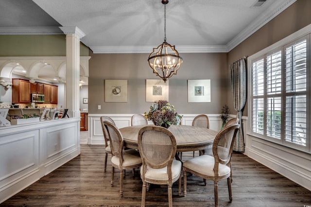 dining area with ornate columns, ornamental molding, dark wood-type flooring, and a chandelier