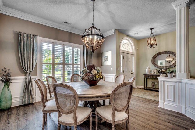 dining room featuring decorative columns, wood-type flooring, a notable chandelier, and a textured ceiling