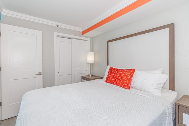 bedroom featuring crown molding, a closet, and light hardwood / wood-style flooring