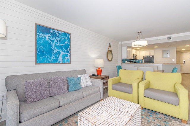 living room with wooden walls and crown molding