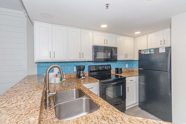 kitchen with black appliances, light stone counters, sink, and white cabinets