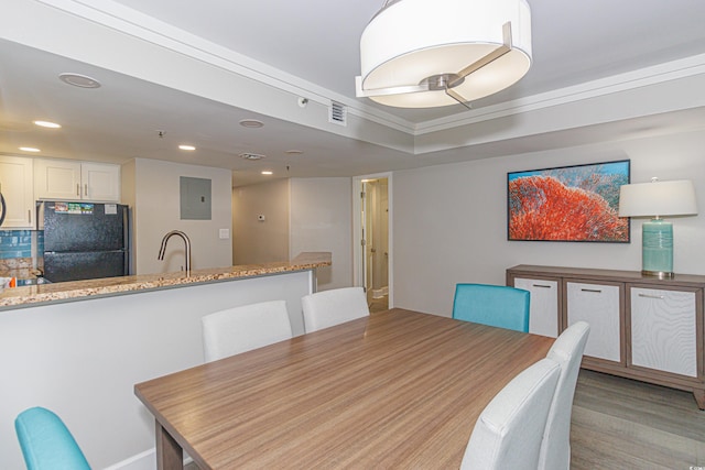 dining area featuring light wood-type flooring, ornamental molding, sink, and electric panel