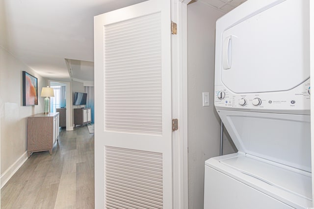 laundry area featuring light hardwood / wood-style floors and stacked washer / drying machine