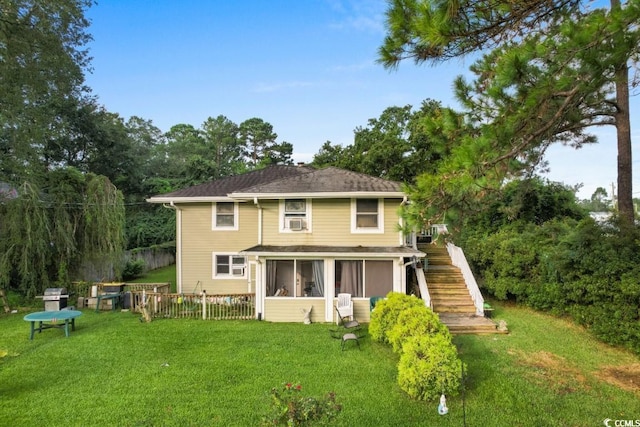 rear view of house featuring a yard, a sunroom, fence, and stairs