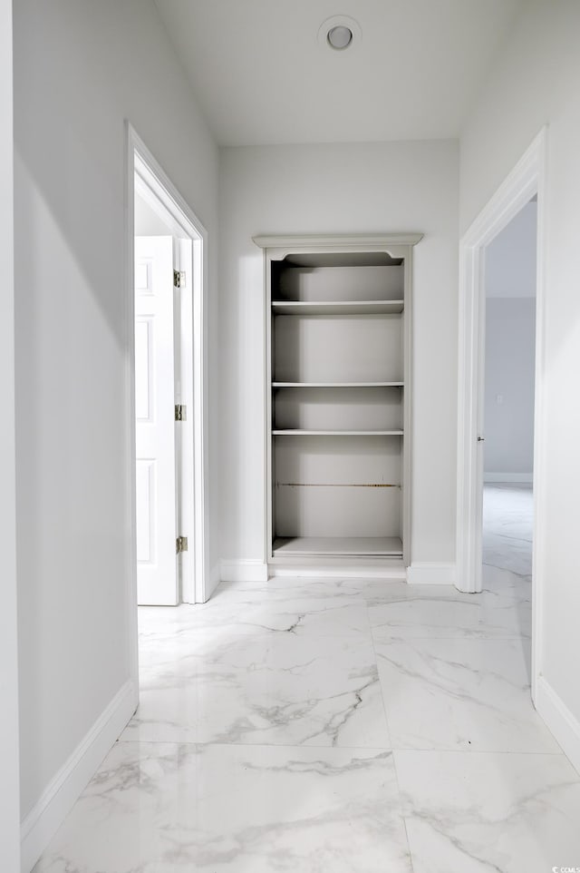 hallway featuring marble finish floor and baseboards