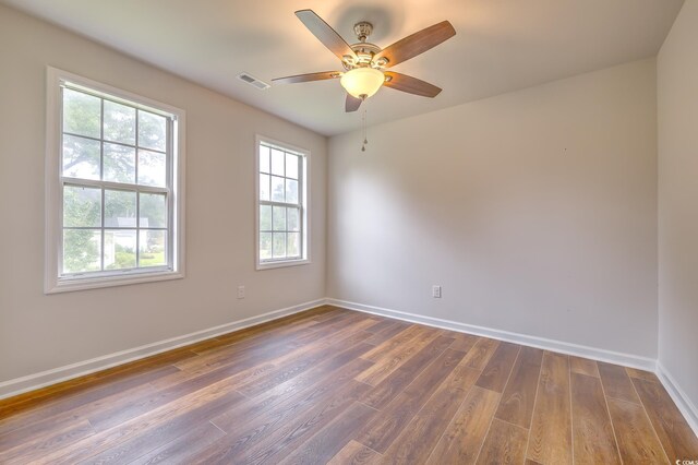 empty room with ceiling fan, plenty of natural light, and wood-type flooring