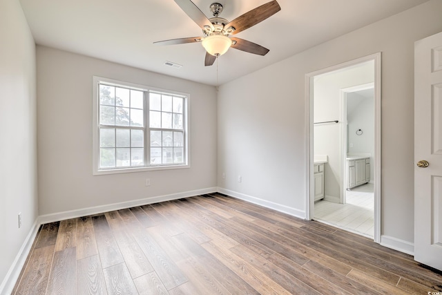 unfurnished room with baseboards, visible vents, ceiling fan, and wood finished floors