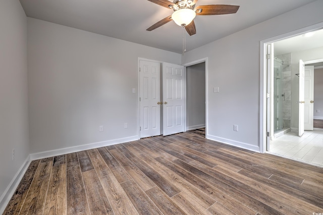 unfurnished bedroom with ceiling fan, connected bathroom, and hardwood / wood-style flooring