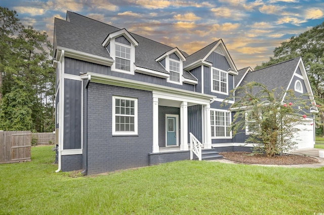 view of front of property featuring brick siding, a yard, board and batten siding, fence, and driveway