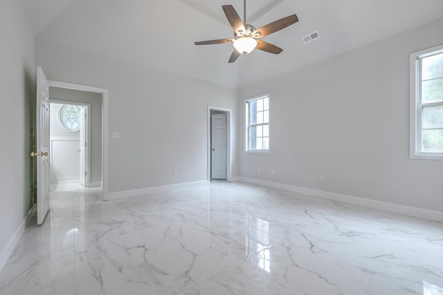 spare room with baseboards, marble finish floor, visible vents, and a healthy amount of sunlight