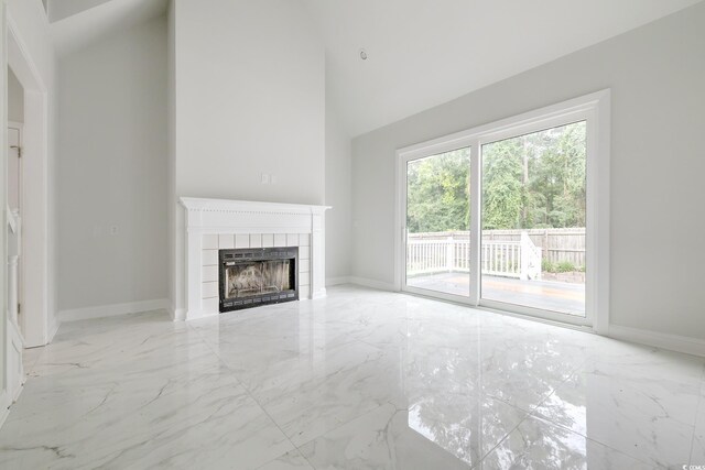 unfurnished living room featuring a fireplace, light tile patterned floors, and a high ceiling