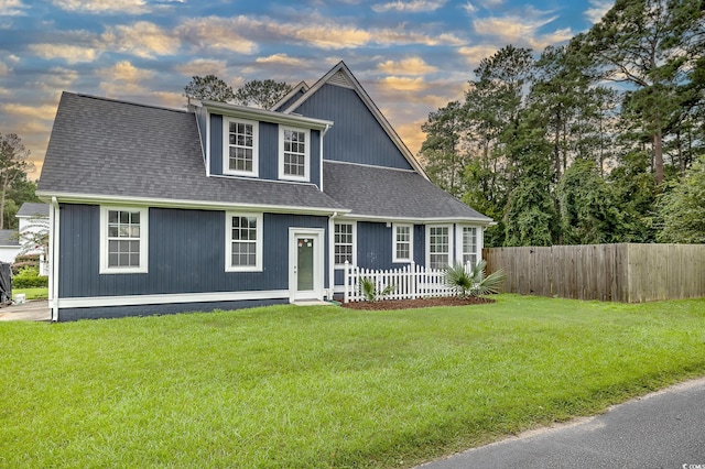 view of front of home featuring fence private yard, a shingled roof, and a lawn