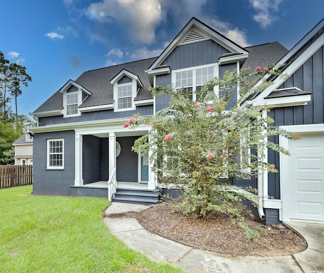 view of front of house with a garage, a shingled roof, brick siding, a front lawn, and board and batten siding