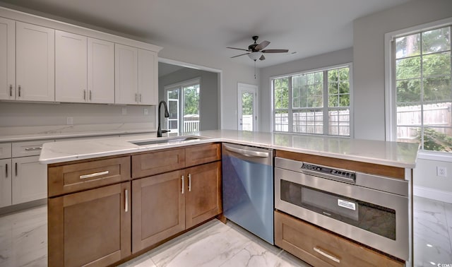 kitchen with a sink, white cabinets, marble finish floor, dishwasher, and brown cabinetry