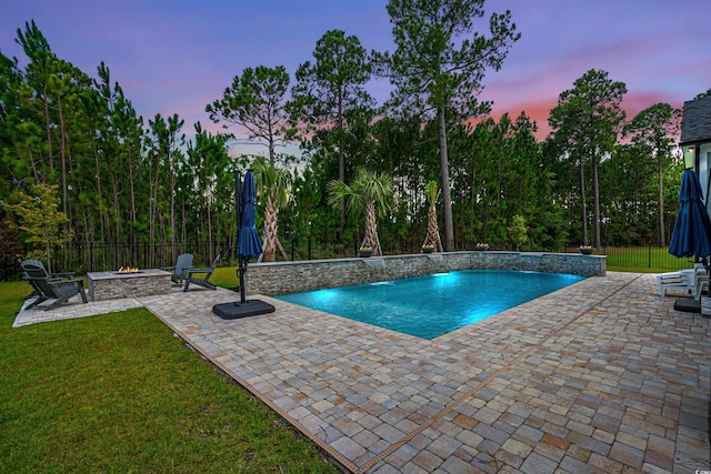 pool at dusk featuring pool water feature, a yard, and a patio area