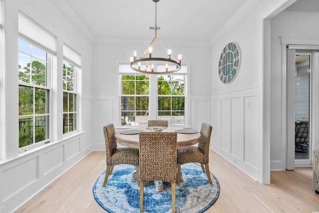 dining room featuring ornamental molding, light hardwood / wood-style floors, and a notable chandelier