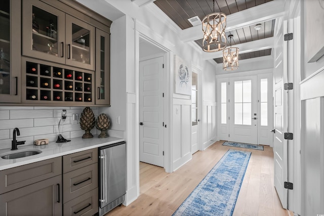 entryway with an inviting chandelier, sink, beam ceiling, and light hardwood / wood-style floors