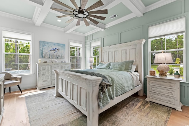 bedroom featuring coffered ceiling, crown molding, and light hardwood / wood-style floors