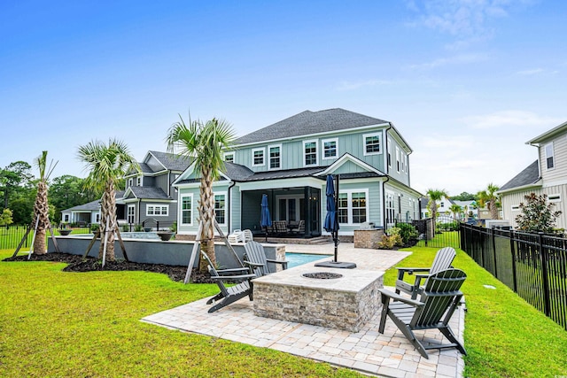 rear view of house with a patio, a yard, a fenced in pool, and a fire pit