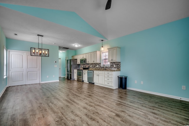 unfurnished living room with hardwood / wood-style floors, vaulted ceiling, sink, and a chandelier