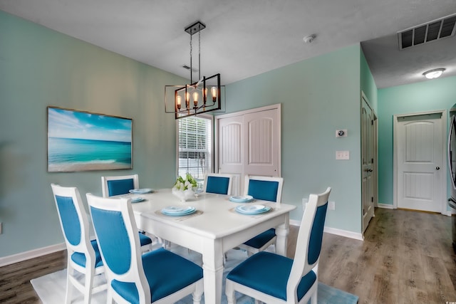 dining space with light wood-type flooring and an inviting chandelier