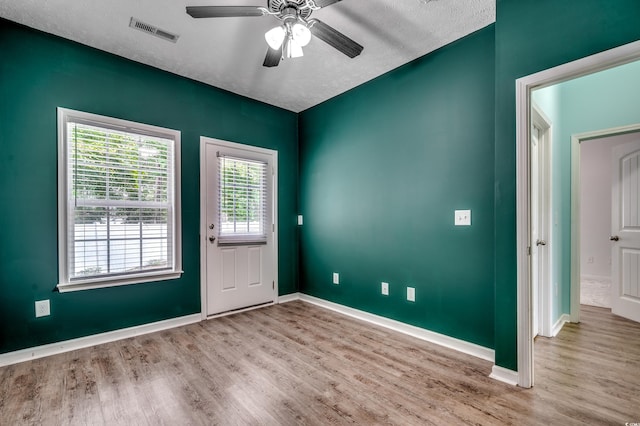 doorway with a textured ceiling, light hardwood / wood-style flooring, and ceiling fan