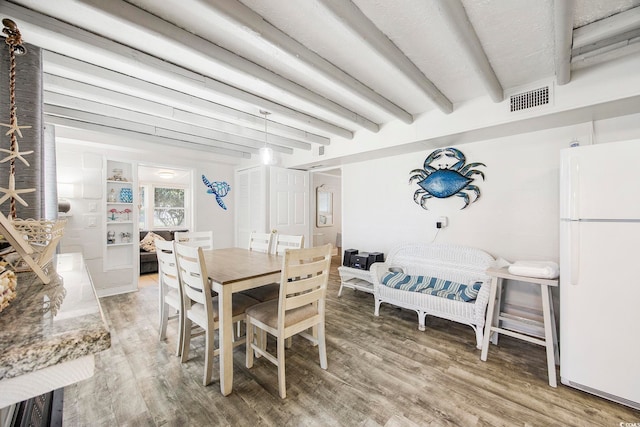 dining area with wood-type flooring and beam ceiling