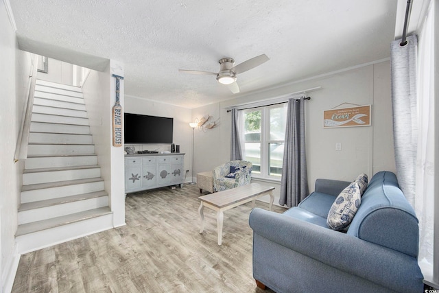 living room with ceiling fan, light hardwood / wood-style flooring, and a textured ceiling