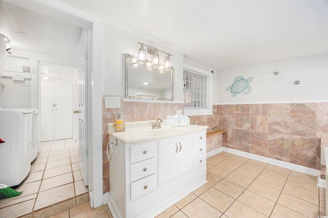 bathroom featuring tile patterned flooring, washer / dryer, vanity, and tile walls