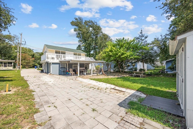 back of house with a garage, a yard, a patio, and a balcony