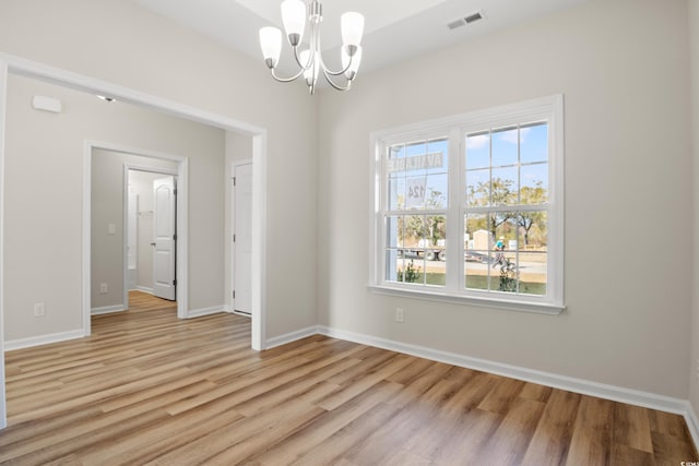 empty room with a chandelier and light wood-type flooring